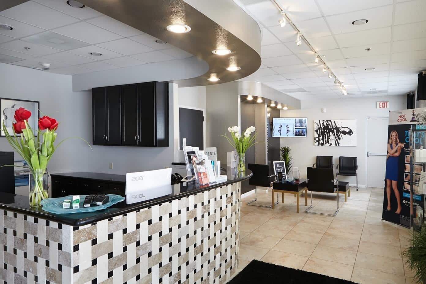 The reception desk at Spa Black North, with red tulips, a tiled front and a bright waiting area