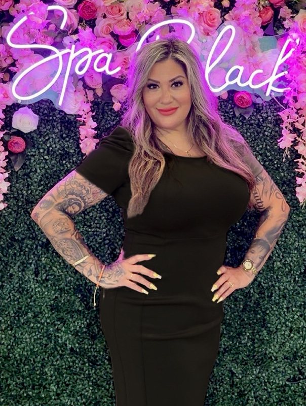 Andria “Joy” Arellano, Spa Manager, in front of the Spa Black neon sign